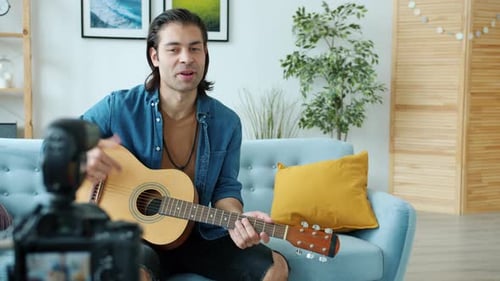 Man Playing Guitar and Recording Video at Home