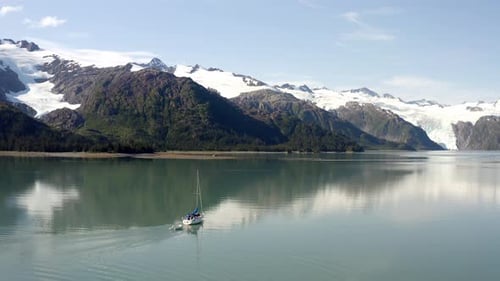 Motorboat Cruising On Calm Waters With Snow Capped Mountains In Distance, Alaska USA - Aerial, Stati