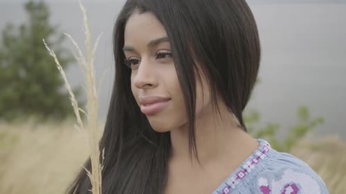 Young Adult Woman Holding Wheat Stalk in Field