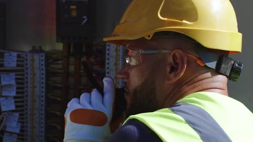 Construction Worker Using Walkie Talkie at Electrical Box