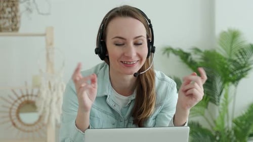 Woman in Headset Teleconferencing on Laptop