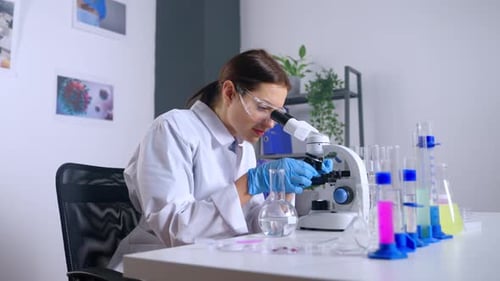 Young Woman Scientist Using Microscope in a Lab