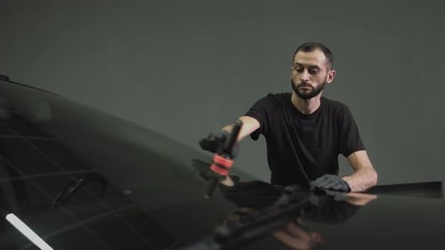 Man Detailing a Black Car in Studio