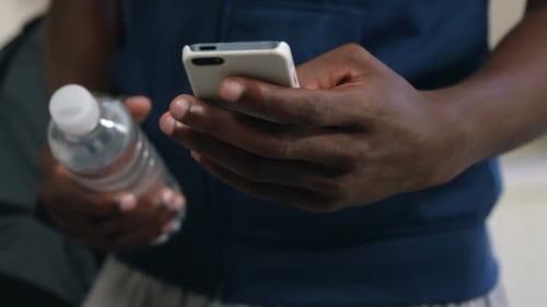 Person Holds Phone and Water Bottle Indoors