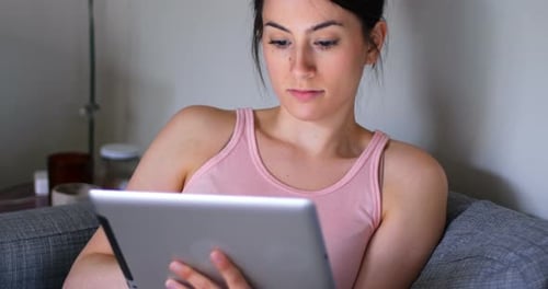 Woman using digital tablet on sofa in living room 4k