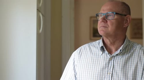 Man Looking Out Window Thoughtfully in Home