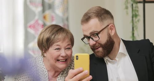 Man and Senior Woman Video Chatting on Phone