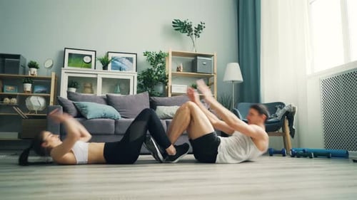Couple doing Sit Ups in Modern Apartment
