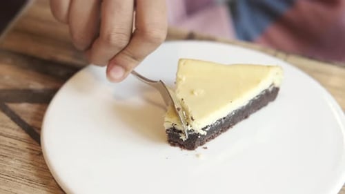 Cutting Tasty Brownie Cheesecake Slice with Fork