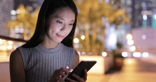 Woman Using Mobile Phone at Night in City