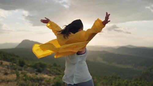 A Girl on Top of a Mountain Raises Her Hands to the Mountains