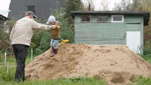 Child and Grandfather Climbing Sand Pile Together