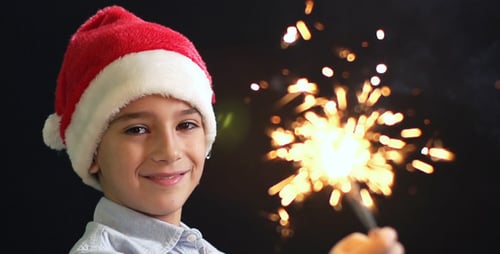 Smiling Boy with Santa Hat Holds Sparkler