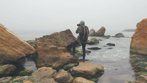 Young Photographer Taking Photos of Ocean Cliff with DSLR Camera
