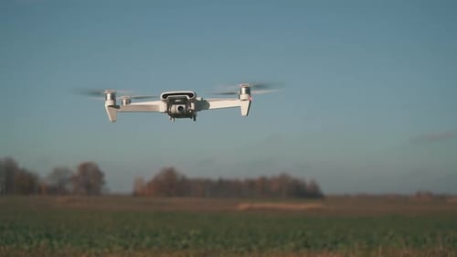 White Drone Flying on Nature Background. Drone Hanging in Air Flying Helicopter Dron Remote Control