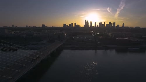 A rearward aerial drone shot of a sunset from Warsaw, the capital city and largest city in Poland. T