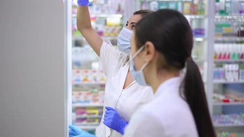 Workers Retrieve Medication in Pharmacy Wearing Protective Gear