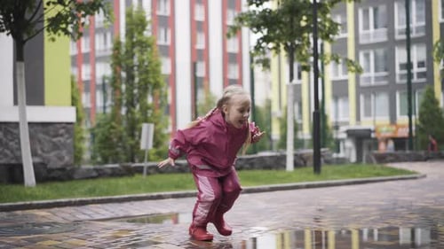 Girl Plays in Puddle on Overcast Day