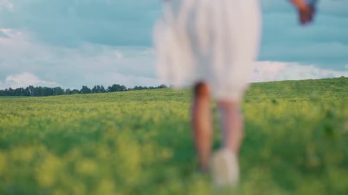 Countryside Young Couple in Nature Man and a Woman are Running Through a Field of Rapeseed Holding