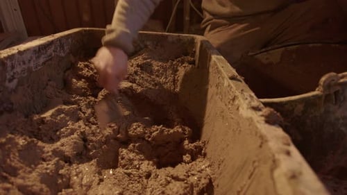 Person Mixing Mud in Container with Hand