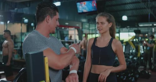 Woman Listens to Man Describe Workout in Gym