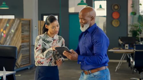 Coworkers looking at tablet in modern office