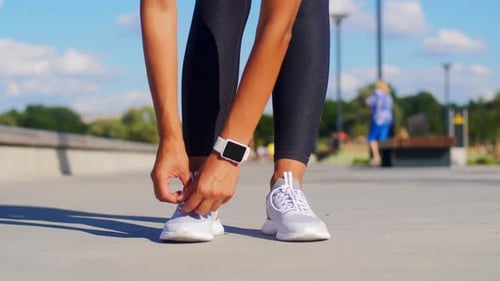 Woman Tying Shoelaces Before Workout in Park