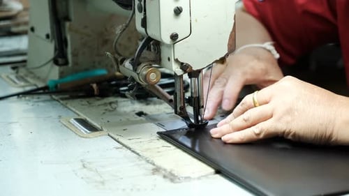 Close-Up Of Tailor Working On Sewing Machine in leather factory background
