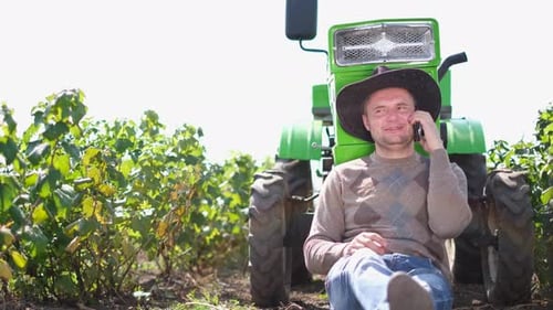 Farmer Talking on Mobile Phone by Tractor