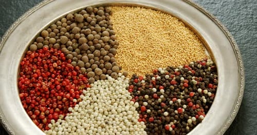 Assorted Peppercorns and Mustard Seeds on Silver Plate