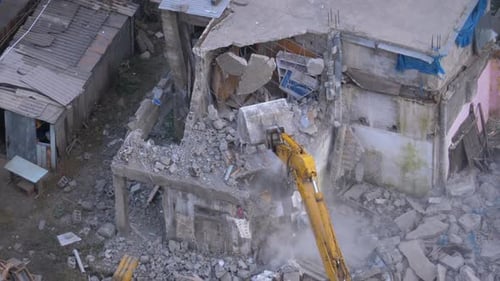 Zerstörung des alten Hauses mit einem Schaufelbagger auf der Baustelle.