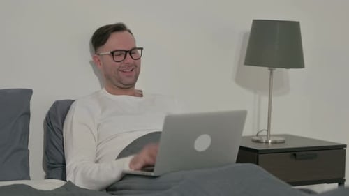 Man Video Calling on Laptop in Bed