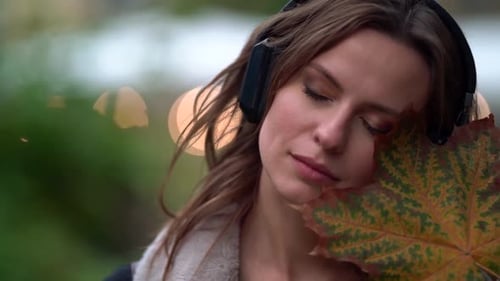 Woman Listening to Music with Autumn Leaf
