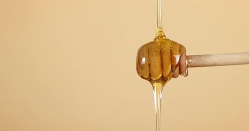 O mel fresco é derramado em uma colher de pau.
