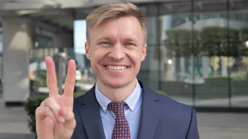 Smiling Man Gives Peace Sign in Urban Setting