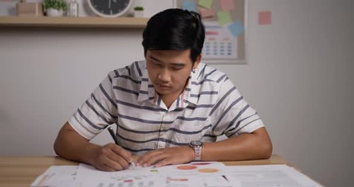 Young Adult Drawing on Document at Desk