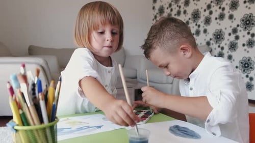 Young Children Painting at Table Together in Home