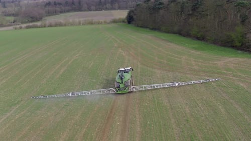 Tractor Spraying Green Field from Aerial View