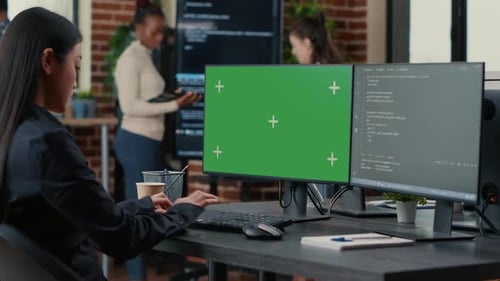 Programador asiático escrevendo código na frente do computador com maquete de chroma key de tela verde