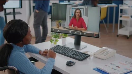 Woman in Wheelchair Attending Video Conference in Office