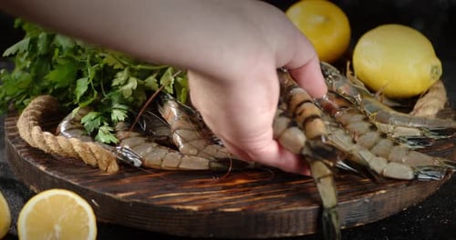 Close Up Hand Arranges Raw Shrimp on Board