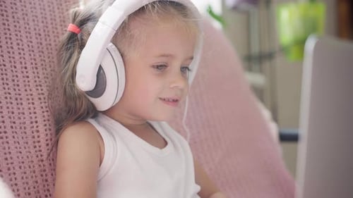 Girl with Headphones Watching Computer Screen