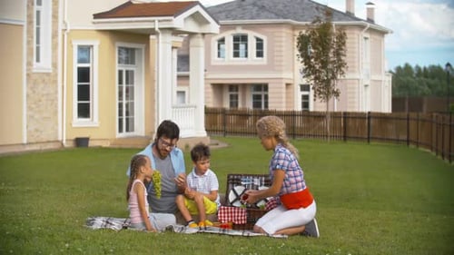 Happy Family Picnic Together Outdoors on Lawn