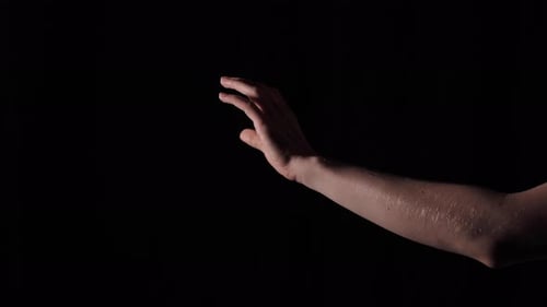 Disembodied Arm Gesturing Against Black Background