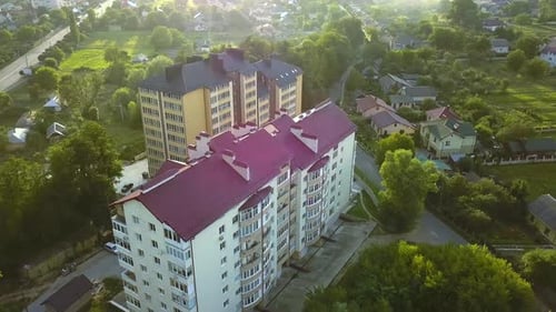 Luftaufnahme eines mehrstöckigen Mehrfamilienhauses in grüner Wohngegend.