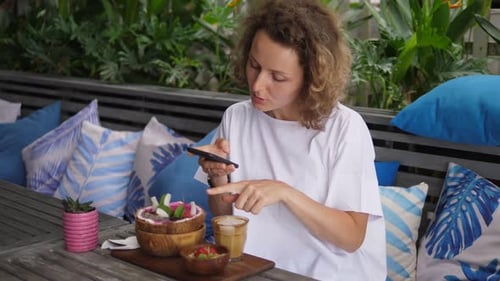 Woman Taking Photo of Food in Tropical Cafe