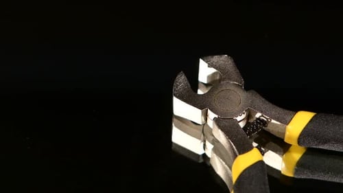 Close up of metal cutting pliers on black surface