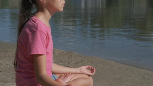 Girl Meditating on Sunny Beach in Lotus Position
