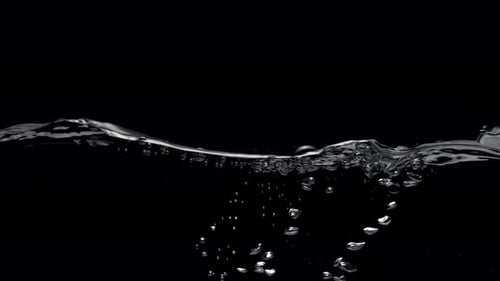 Wasseroberfläche spritzt vor schwarzem Hintergrund. Zeitlupe.