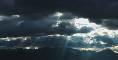 Sunbeams Through Storm Clouds over Mountain Landscape